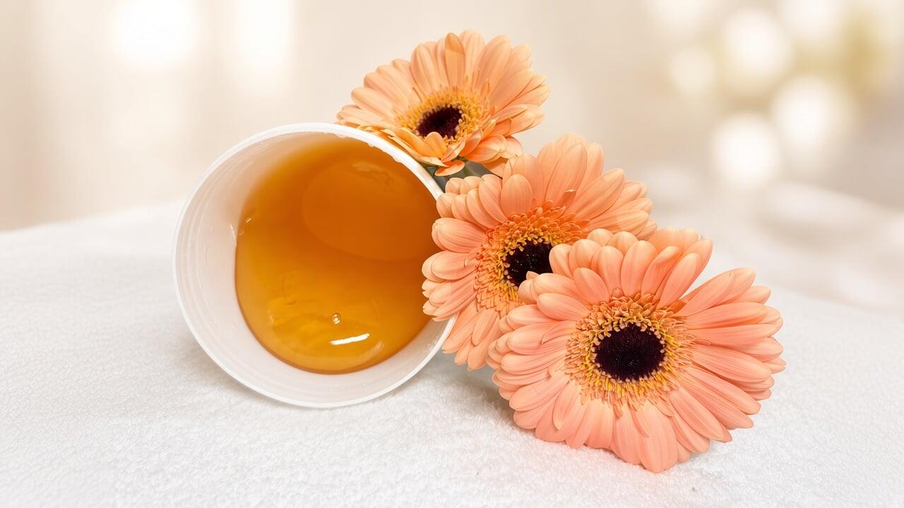 Tub of natural sugaring paste with peach gerbera daisies on a white spa towel at Vancouver Green Spa, downtown Vancouver